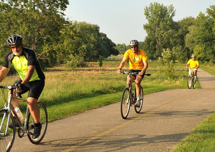 Three men biking along trail on sunny day