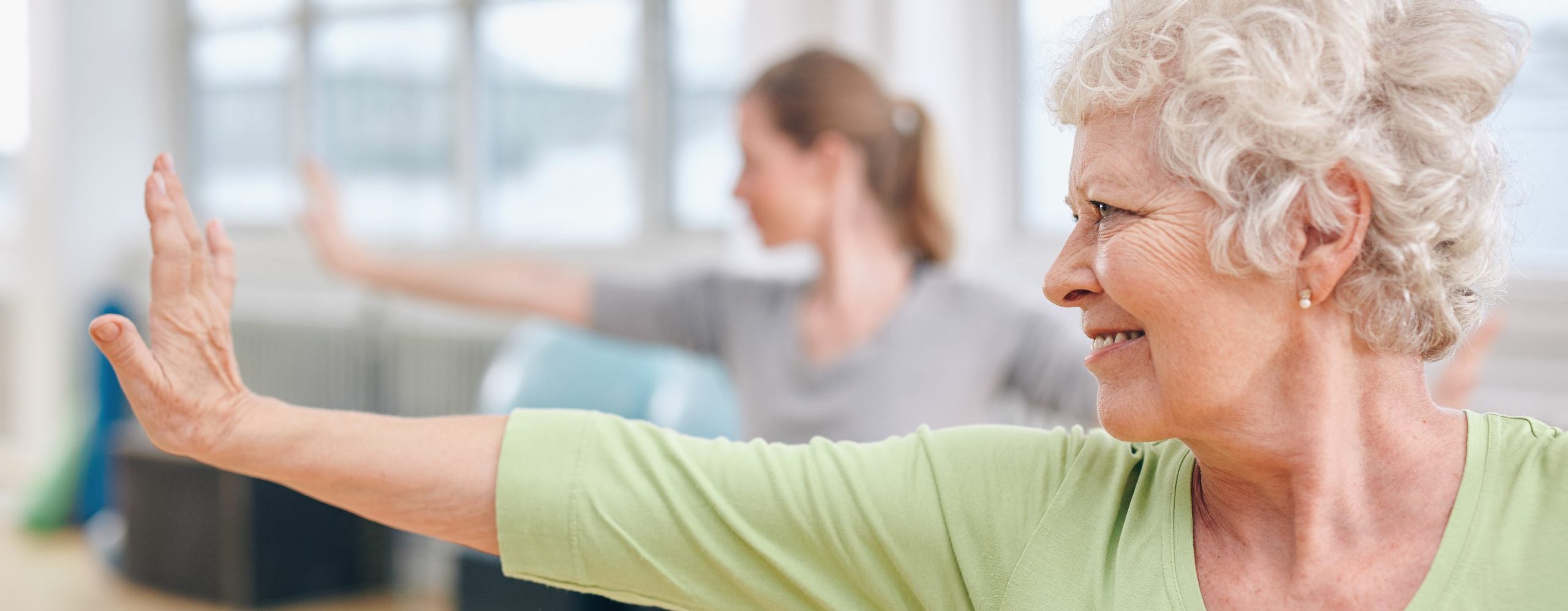 Senior woman doing stretching exercise at yoga class